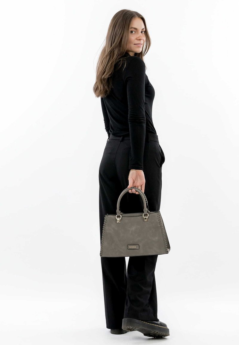 Borsa grigia con forma strutturata, manici superiori e dettagli cuciti. Textura liscia, con hardware in tono oro e placca con logo.