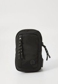 Mala crna pravokutna torbica s prednjim džepom na patentni zatvarač, dvostrukim povlačiteljima patentnog zatvarača sa crnim i bijelim vrpcama, te suptilnim logotipom na donjem desnom dijelu.