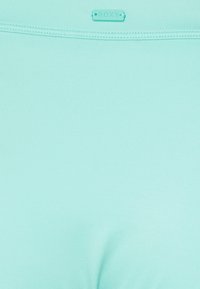 Leggings verde-menta feitos de um tecido suave e elástico, com uma pequena etiqueta de logotipo e uma textura lisa num design ajustado.