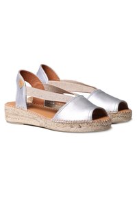 Sandali espadrilles metallici argento con punta aperta, cinghie incrociate elastiche e suola intermedia in juta intrecciata. Finitura testurizzata sul materiale superiore.