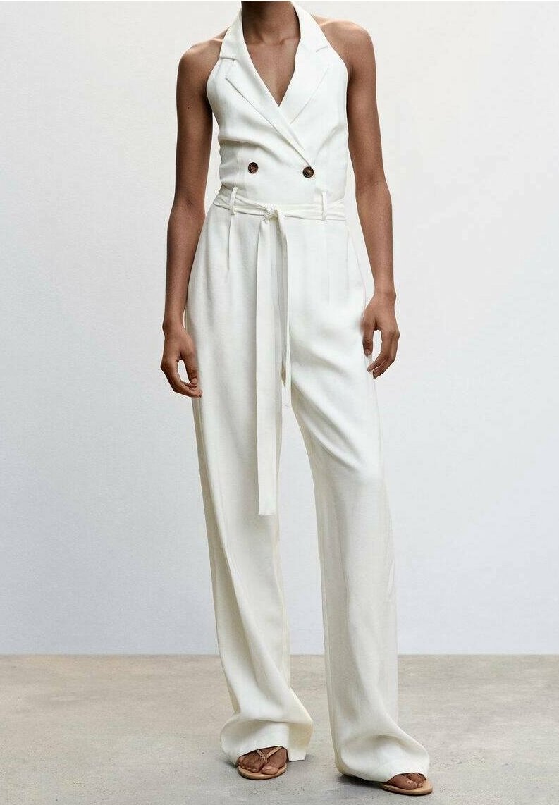 Monos de color blanco de doble botonadura con escote halter, cinturón de lazo en la cintura y pantalones de pierna amplia, confeccionados en una tela suave.