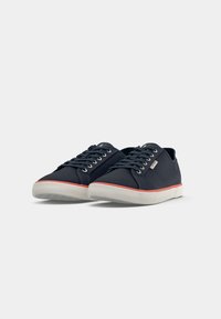 Pair of navy blue canvas sneakers with white rubber soles and red trim, black laces, and metal eyelets on a white background.