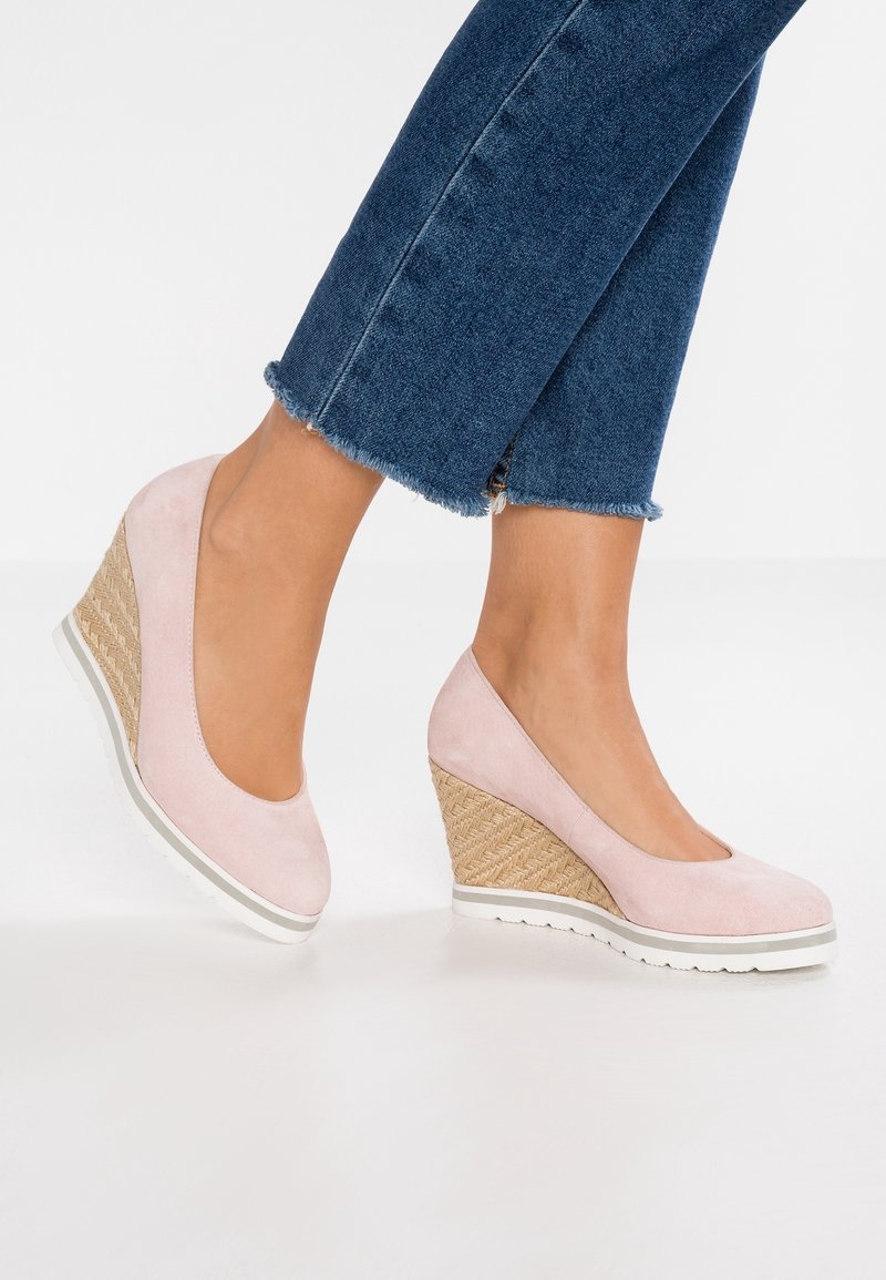 Bottines compensées en suède rose avec un talon en jute tissé, dotées d'un bout rond et d'une semelle en caoutchouc blanc, portées avec un jean en denim cropped.