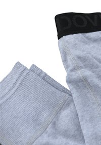 Grå leggings med et tekstureret stof, der har en sort elastisk talje med "DOVE" logo. Nærbillede af syninger og stofdetaljer.