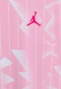 Tessuto atletico rosa con un motivo geometrico ripetuto e linee verticali. Presenta un logo Jumpman di un rosa brillante posizionato centralmente.