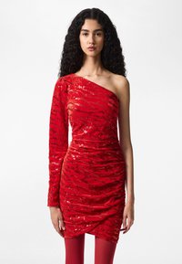 Rød enkel skulderkjole med paljettstoff, rynket design, teksturert finish og slank silhuett. Brukt med matchende røde leggings.