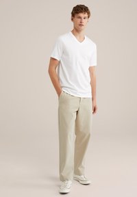 Vit v-ringad t-shirt, ljusbeiga chinos, vita sneakers med röda ränder. Avslappnad passform, korta ärmar, mjukt tyg, minimalistisk design.