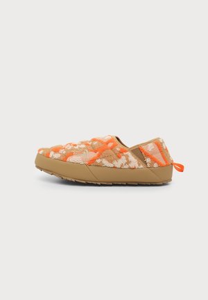 Afslappet slip-on sko med tanfarvet gummisål og tekstureret stofoverdel i orange, beige og hvidt mønster, med en lille træksløjfe ved hælen.