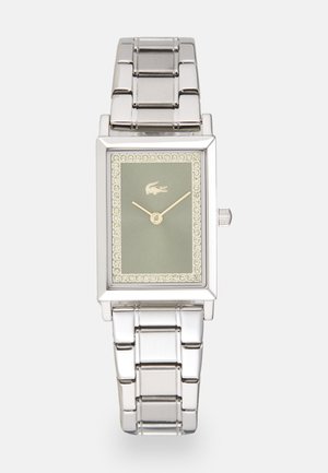 Montre-bracelet en métal argenté avec un cadran rectangulaire, un fond vert, des accents dorés et des embellissements en cristal autour de la lunette. Style de bracelet en maillons.