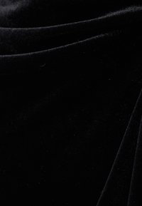 Zwart fluwelen stof met een zachte textuur, met subtiele plooien en een gladde, glanzende oppervlakte. Ideaal voor elegante kleding of bekleding.