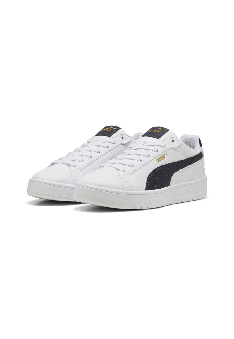 Baskets blanches avec une finition en cuir lisse, présentant une bande latérale noire avec le logo PUMA doré, un bout arrondi et une semelle épaisse blanche.