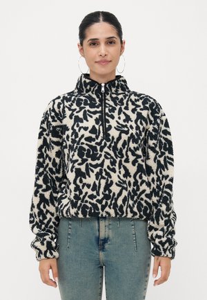 Pull en polaire bouffante avec demi-fermeture éclair, présentant un motif abstrait noir et crème, coupe décontractée et poignets élastiqués.