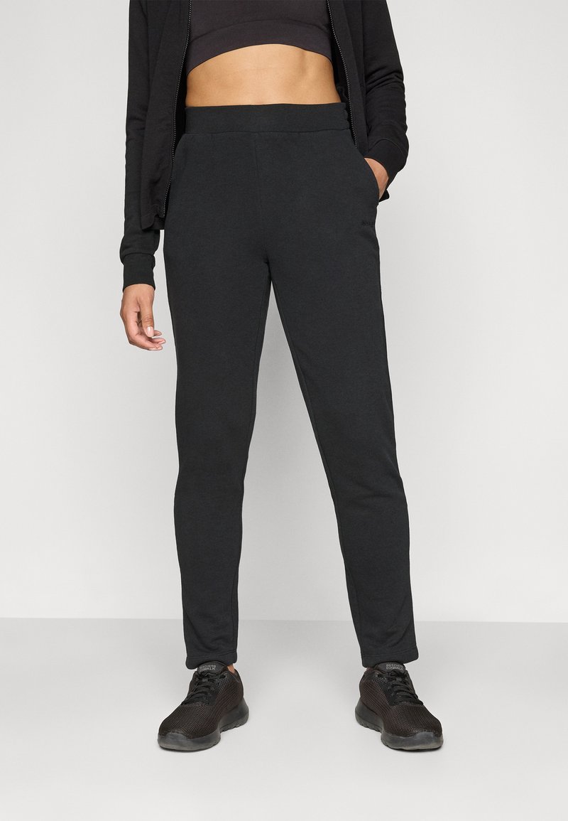 Sorte joggebukser med en glatt tekstur, elastisk midje og sidelommer, sammen med sorte joggesko. Enkel, strømlinjeformet design.
