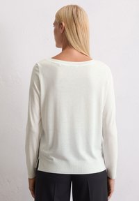 Helles, leichtes Langarmoberteil mit weitem Ausschnitt, schmalen Bündchen und seitlichen Schlitzen, das eine glatte Textur und ein schlichtes Design aufweist.