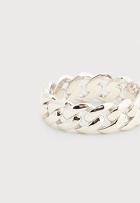 Παχύτερο ασημένιο δαχτυλίδι αλυσίδας με γυαλισμένους, αλληλοσυνδεόμενους κρίκους που σχηματίζουν έναν συνεχή βρόχο σε απλό φωτεινό φόντο.