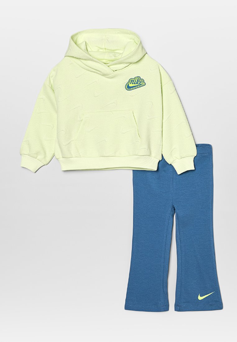 Hoodie vert clair en tissu texturé avec une poche frontale, associé à un pantalon élastiqué bleu arborant un petit logo Nike jaune.