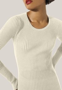 Gerippter Langarmtop in Off-White mit Rundhalsausschnitt. Der Stoff hat ein weiches, strukturiertes Finish mit vertikalen Streifen.