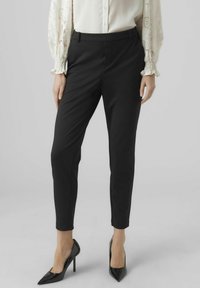 Svarta tapered byxor i en mjuk tyg med slim fit, med medelhög midja och ankellång klippning, upp tillsammans med spetsiga svarta klackar.