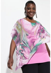 Leggera vestaglia floreale rosa con dettagli verdi, caratterizzata da un scollo rotondo e strass decorativi, sovrapposta a un top rosa uniforme e pantaloni neri.