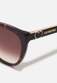 Vėžlio kiauto saulės akiniai su gradientiniais objektyvais. Juodi ir rožinės aukso spalvos šakės su širdies dizainu ir auksinėmis "LOVE MOSCHINO" užrašais.