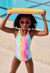 Multicolored swimsuit featuring a wavy pattern in pastel shades; child holding a yellow and pink foam pool float above head; pink sunglasses.