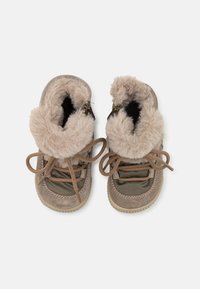 Chaussures en suède marron et en tissu avec un col en fourrure beige duveteux, dotées de lacets marron et d'une semelle en caoutchouc texturé.