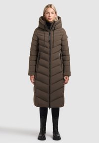 Abrigo acolchado largo, marrón, con costura en espiga, cuello alto y capucha desmontable. Cuenta con bolsillos con cremallera y cierre frontal con cremallera.