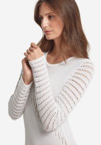 Weißer gestrickter Pullover mit strukturiertem, offenem Stichdesign und langen Ärmeln. Verfügt über einen runden Halsausschnitt und eine figurbetonte Passform.