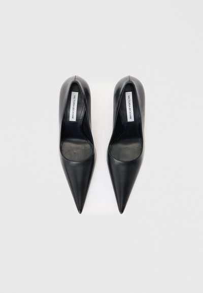 Ζευγάρι μαύρες μυτερές γόβες από δέρμα με ετικέτες Victoria Beckham στο εσωτερικό, εκτεθειμένες σε λευκό φόντο.