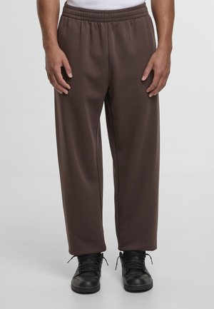 Brązowe spodnie dresowe o luźnym kroju, wykonane z miękkiej tkaniny. Posiadają elastyczną talię oraz boczne kieszenie. W zestawieniu z czarnymi trampkami.