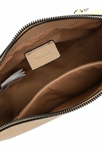 Beige Lederhandtasche mit einem Reißverschluss, Stofffutter, einer kleinen Tasche und einem rechteckigen Etikett, das innen eingestickt ist.