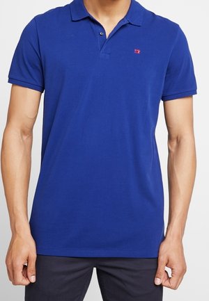 Polo bleu en coton, avec un col classique, une patte de boutonnage à deux boutons et un petit logo rouge brodé sur la poitrine.