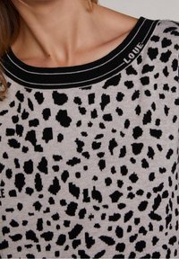 Jasnoszary sweter z czarnym nadrukiem w panterę, czarnym prążkowanym dekoltem typu crew z napisem "LOVE" oraz miękką teksturą dzianiny.