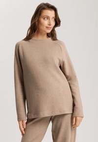 Beiger Langarmpullover aus weichem Material mit entspanntem Schnitt, Rundhalsausschnitt und Raglanärmeln, kombiniert mit passenden Hosen.