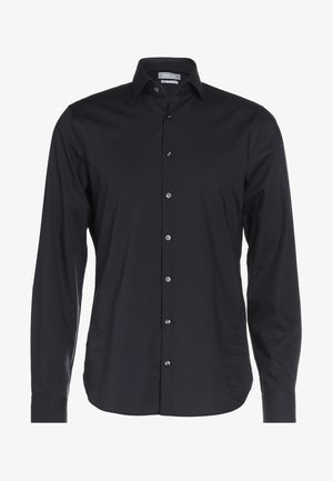 Svart langermet skjorte laget av glatt stoff. Har krage med knapper, frontlukking med knapper, og en subtil logo på brystet.