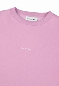 Růžová mikina s kulatým výstřihem, žebrovaným límcem a malým bílým logem "OH APRIL" tištěným na hrudi. Měkká textura, volnočasový design.