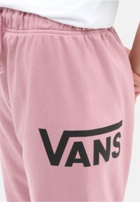 Vaaleanpunaiset puuvillaiset collegehousut, joissa on joustava vyötärö ja suuri musta "VANS" -logoprintti sivussa. Sujuva kangas ja rento istuvuus.