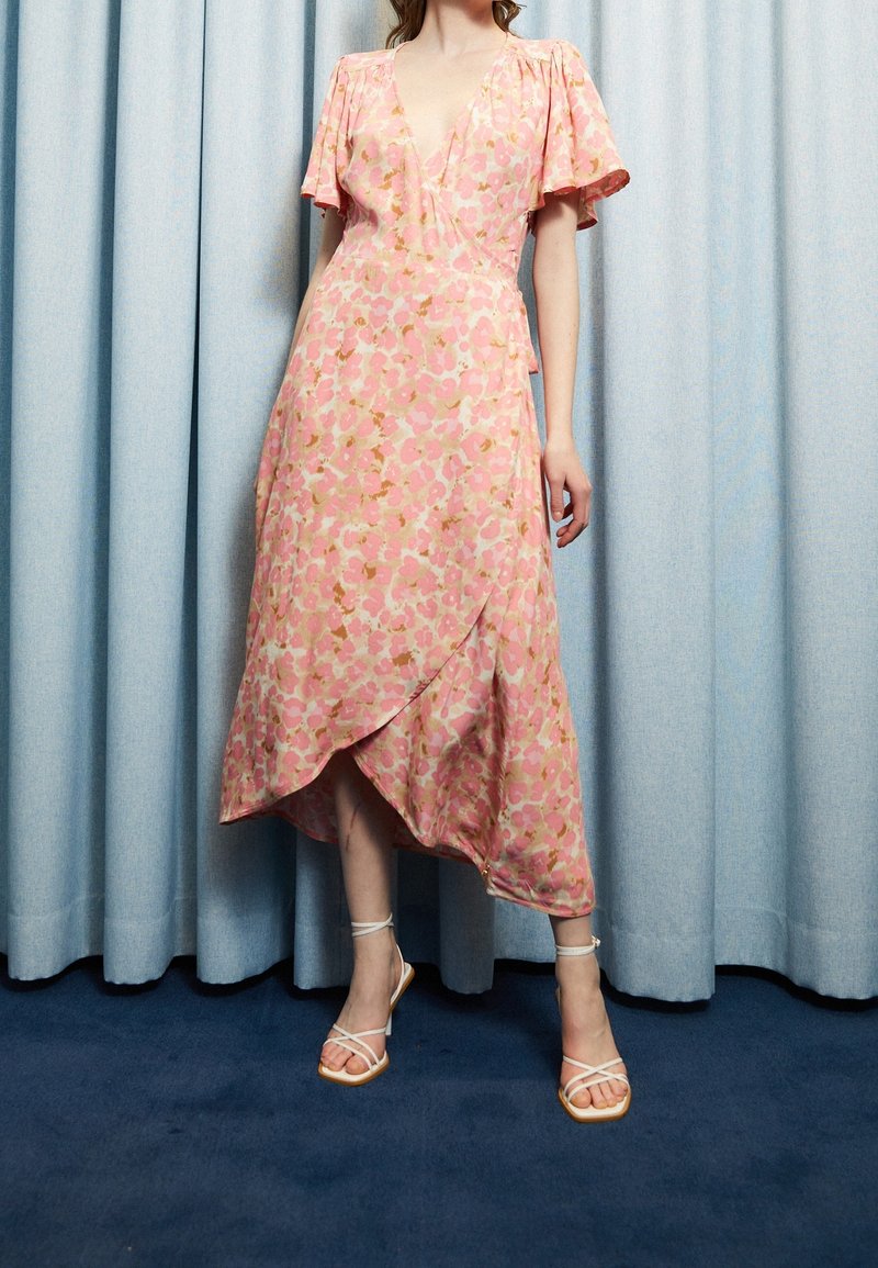 Vestido envolvente floral rosa con mangas cortas, escote en V profundo y dobladillo asimétrico. Tela suave y ligera con detalles dorados.