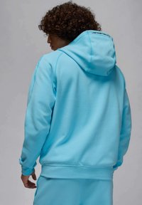 Felpa con cappuccio azzurro chiaro realizzata in tessuto morbido, con cappuccio, polsini a costine e logo sul retro del collo. Tessuto liscio con vestibilità comoda.