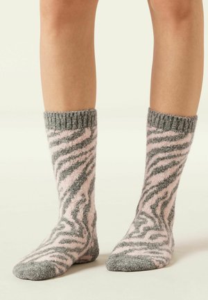 Chaussettes en peluche avec un motif de rayures zèbre rose et gris, dotées d'un revers côtelé et d'une texture douce, conçues pour la chaleur et le confort.