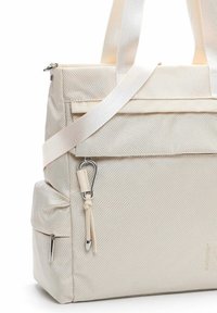 Beige textured tote bag with front flap pocket, side zip pocket, dual top handles, and an attached silver carabiner with leather tassel.