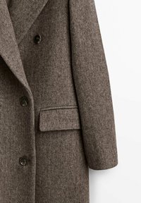 Brun, struktureret ul coat med en notch krave, dobbeltbrystet design, to knapper og en enkelt lomme på den forreste sidesøm.
