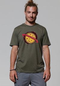 Olijfgroene katoenen t-shirt met een grafisch ontwerp van een pizza met een ring, gestileerd als een planeet, tegen een donkere achtergrond.