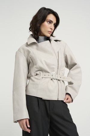 Giacca in pelle grigia chiara con vita regolabile, maniche ampie e chiusura a zip diagonale. Presenta un ampio colletto e tasca laterale con zip.