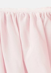 Jasnoróżowy materiał o teksturowej powierzchni, z marszczeniami na górnej krawędzi. Miły w dotyku i gładki wygląd.