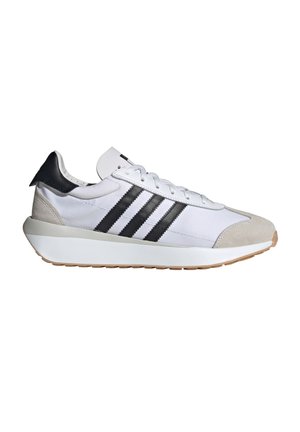 White low-top sneaker with black stripes, beige suede toe, black heel tab, white laces, and thick white sole with gum outsole.