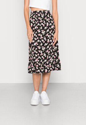 Schwarzer Midirock mit rosa-weißem Blumenmuster, gerafftem Saum, kombiniert mit weißen Plateaust sneakers und einem weißen, kurzgeschnittenen Oberteil.