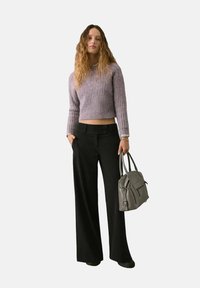 Maglione a coste in lavanda, tagliato, pantaloni neri a vita alta con gamba larga e una borsa grigia con due manici superiori, dotata di zip e tasca frontale.