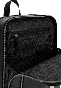 Zaino nero con apertura con zip, dotato di una fodera interna con marchio e numerosi scomparti per un'organizzazione ottimale.