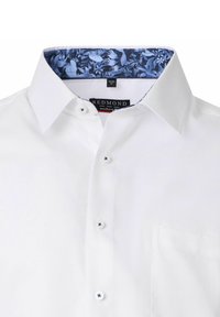 Witte overhemden met een gestructureerde stof, knoopsluiting en een kraagvoering met blauw bloemenpatroon. Beschikt over een enkele borstzak.